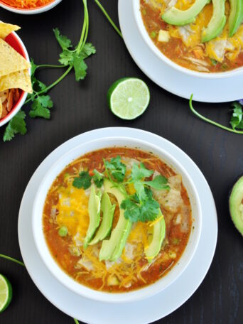 This authentic chicken tortilla soup starts with fresh tomatoes and chicken broth and is loaded with veggies, cheese, and shredded chicken.