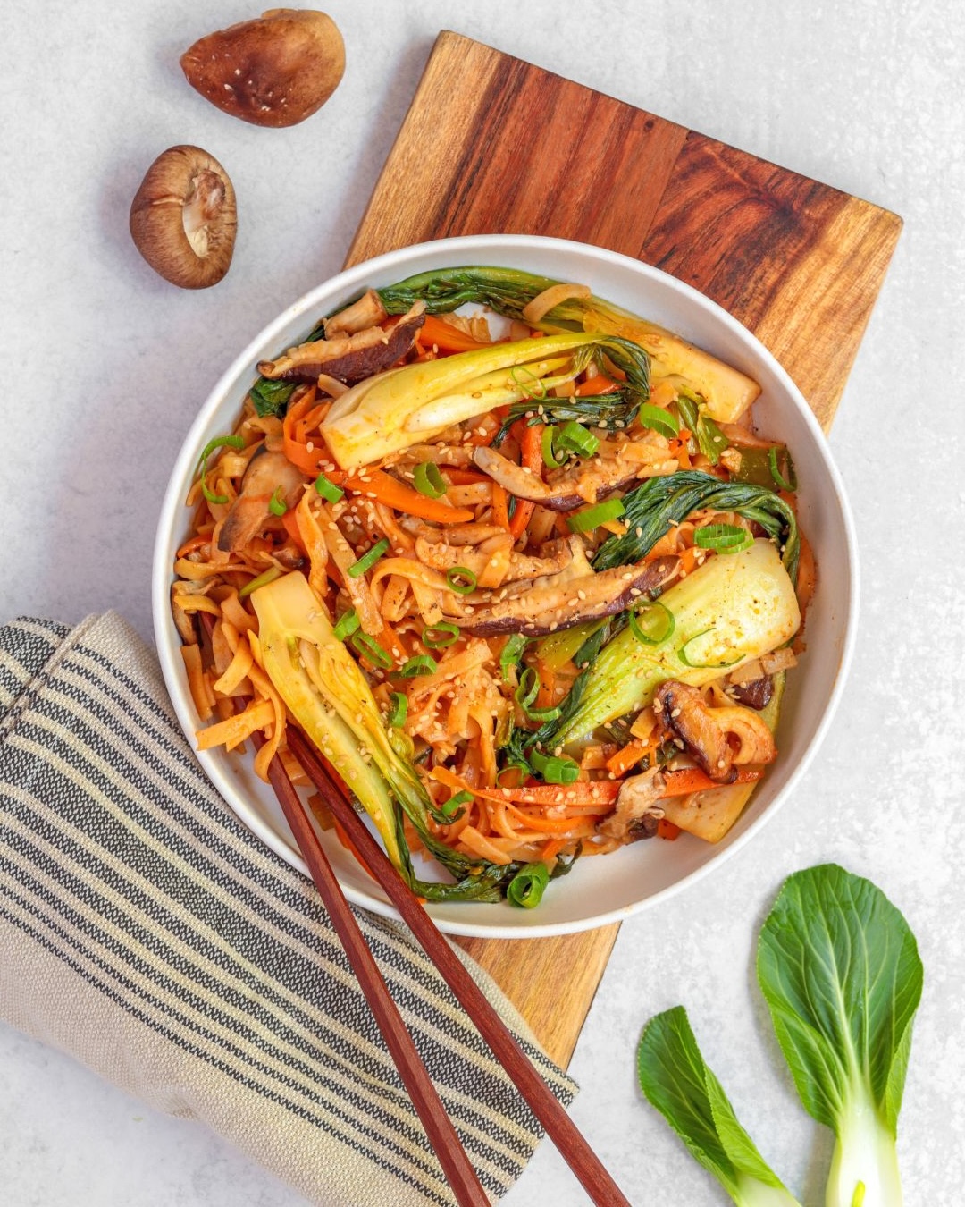 This quick and easy plant-based meal cooked in a delicious Korean stir-fry sauce features Asian mushrooms, carrots, bok choy, and rice noodles. 