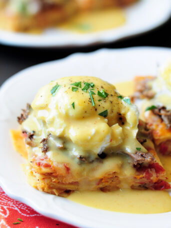 This is a unique Eggs Benedict recipe with slow cooked barbacoa and a green chili hollandaise served on a chilaquiles base.