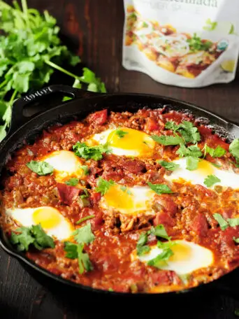 Easy 7-ingredient Shakshuka recipe simmered in a tangy, aromatic red chili sauce with rich notes of cocoa, smoked paprika, and ancho chili.