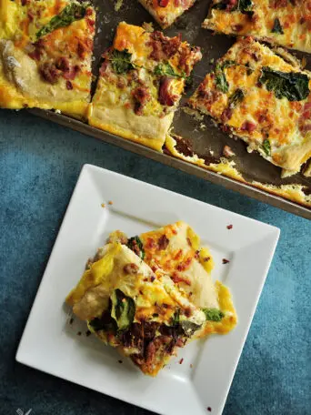 Sheet pan breakfast pizza recipe incorporates your favorite breakfast ingredients like bacon and eggs, plus onions and greens for a balanced one-pan meal.